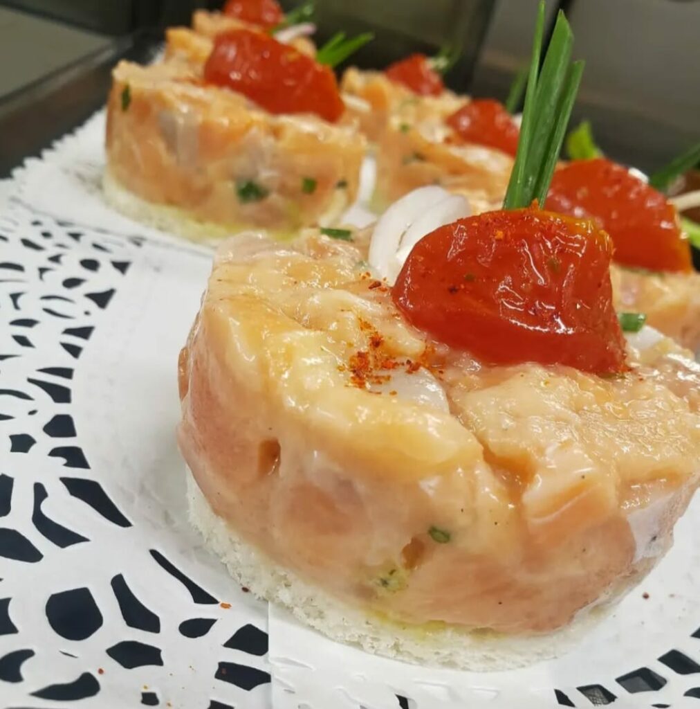 Tartare de saumon dressé à l’emporte-pièce, surmonté d’un pétale de tomate